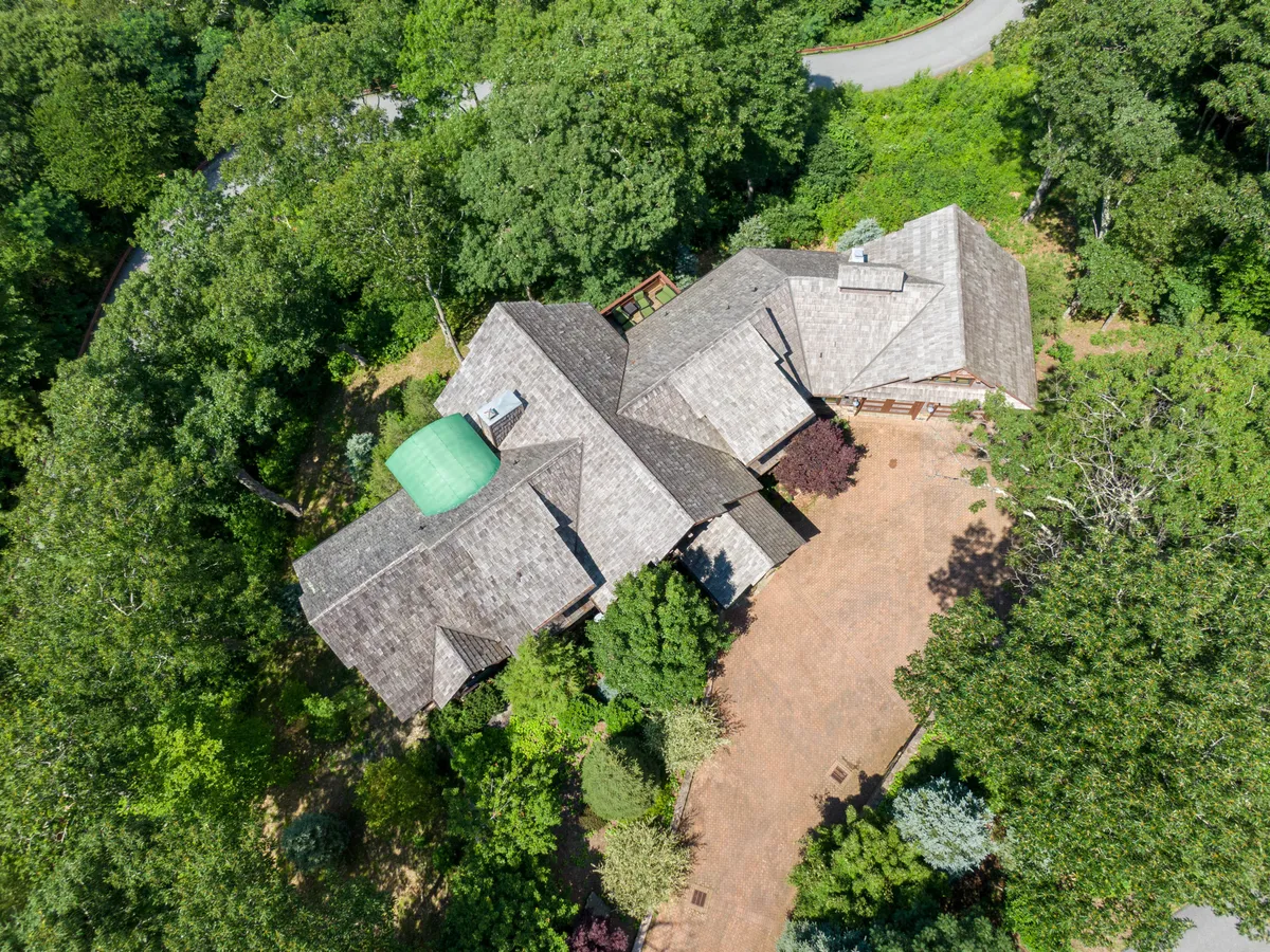 An exterior view of the unique property with its green dome, natural landscaping, and intricate roof design. The surrounding area features trees and open space, ideal for outdoor gatherings or relaxing after local adventures.
