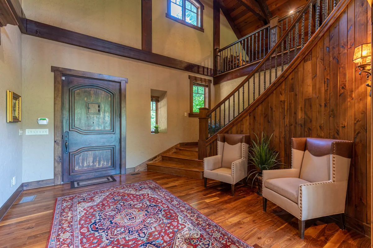 The entryway features a beautiful front door, staircase, armchairs, and a welcoming area rug—setting the tone for guests as they step into the home's embrace. Warm lighting and thoughtful decor make a strong first impression.