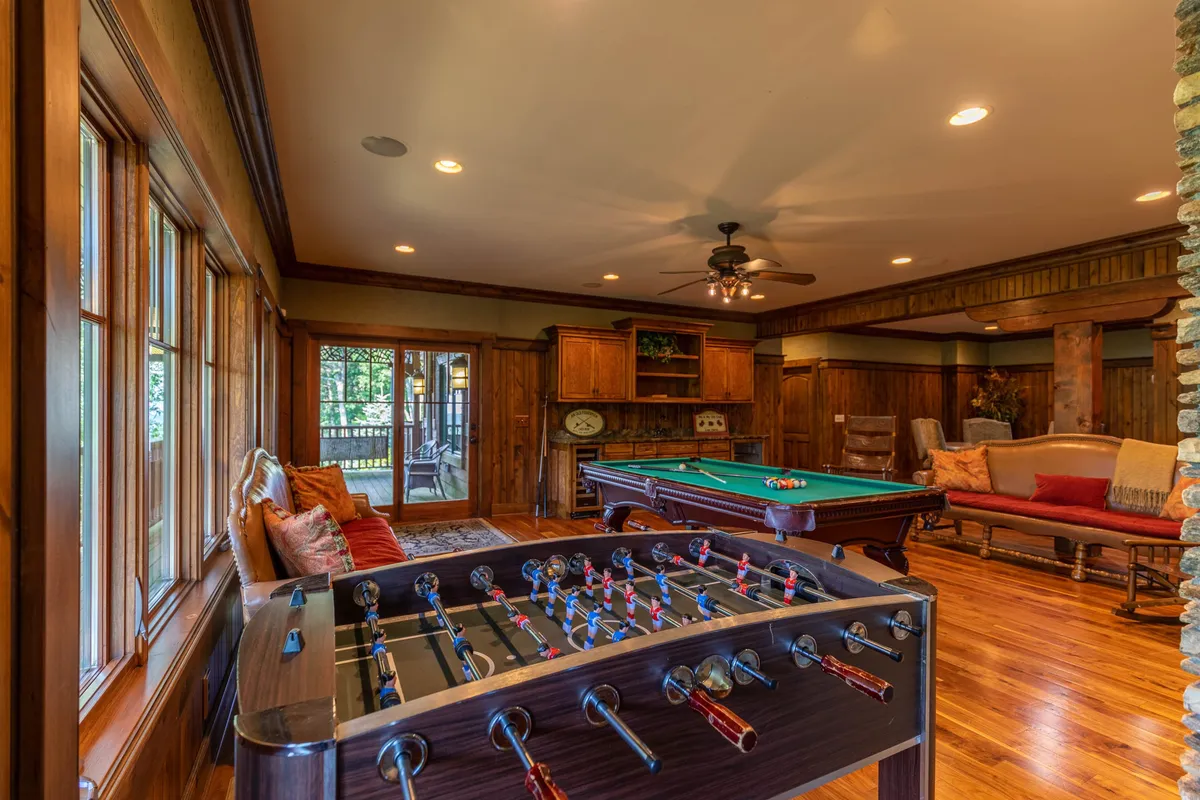 This image features the core of the entertainment oasis: a spacious game room with a foosball table, pool table, comfortable seating, and warm wooden cabinetry. The setting captures guests engaging in leisure activities and relaxing, emphasizing the playful and social atmosphere described in the section.