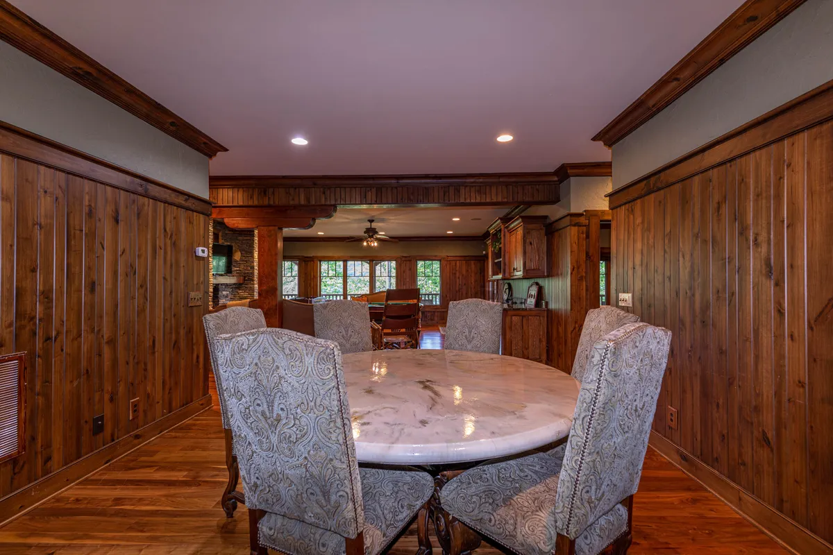 A sophisticated marble-topped dining table surrounded by ornate chairs and wooden wall paneling, this image captures the elegance of communal indoor gatherings. The table is the focal point for board games, conversations, or card games, reflecting the home's welcoming hospitality.